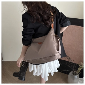 Close-up of mocha brown tote bag with leather patch and adjustable strap on a model
