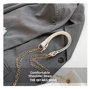 Detail eines bequemen cremefarbenen Leder-Schultergurts mit goldener Kette am Blazer