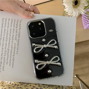 Dettaglio della cover nera per iPhone con fiocchi in metallo argento e borchie decorative