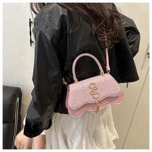 Petit sac pailleté rose avec chaîne dorée et franges, porté par un mannequin à l'épaule