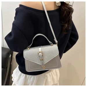 Detail of silver crossbody bag with sequined top flap and gold buckle closure