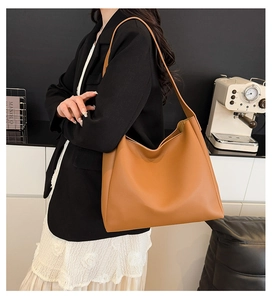 Detailed view of a spacious brown leather tote bag worn as a stylish shoulder bag
