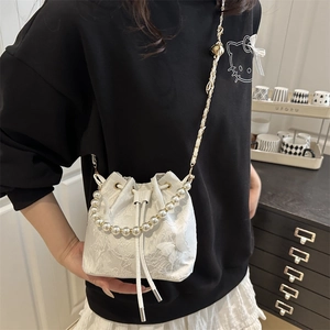 Lace bucket bag with floral embroidery, pearl handle, and metal bell crossbody strap