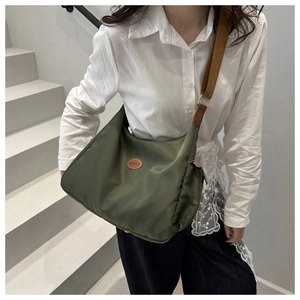Detail view of dark green oxford tote with leather patch and adjustable brown shoulder strap