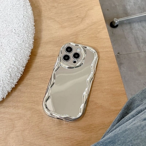 Silver mirror phone case with wavy edges for iPhone, shown on a wooden background