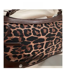 Detail of leopard print crescent bag with leather trim and silver metal rivets