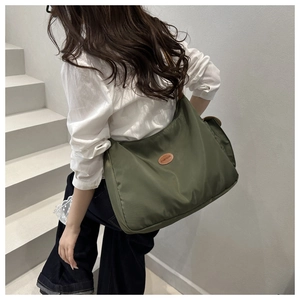 Detail of army green nylon tote bag worn cross-body on a minimalist white shirt