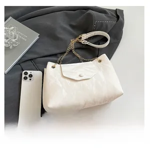 Detail der weißen Tasche in Knitteroptik mit goldener Kette und elegantem Klappverschluss