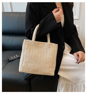 Detail of hand-woven beige tote with herringbone texture and white round leather handles