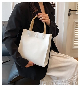 Chic beige tote bag with round circular detail held by model in casual office setting