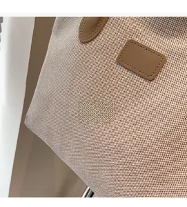 Close-up of woven canvas texture and brown leather strap detail on minimalist tote bag
