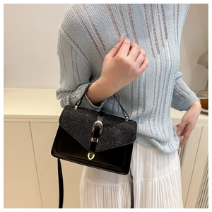 Close-up of black crossbody bag featuring sequined flap and gold buckle detail