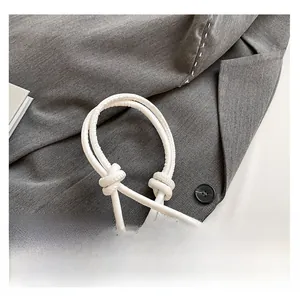 Detail of the white leather shoulder strap with a knotted design and gold metal hardware
