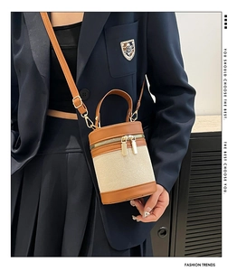 Detail of contrast stitching bucket bag with beige weave and brown leather trim