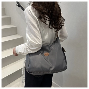 Detailed shot of large capacity grey nylon tote bag styled on model in urban setting