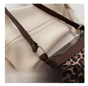 Detail of leopard print shoulder bag featuring dark brown leather strap and silver D-ring