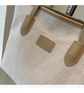 Detail shot of sturdy cream canvas fabric and brown leather handle stitching on tote bag