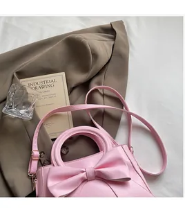 Detail of pink bow handbag with smooth matte leather and round handle accessory