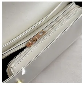 Close-up of smooth rose gold zipper and neat stitching on a white leather baguette bag