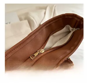 Close-up of smooth gold zipper and lychee texture on brown faux leather tote bag