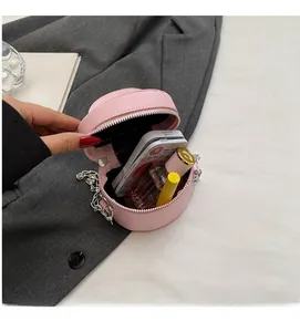 Internal view of pink round chain bag showing capacity for perfume and compact powder