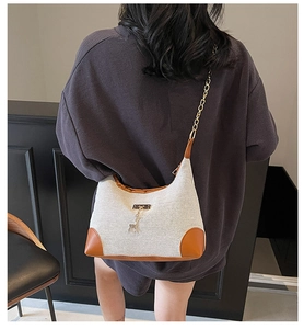 Détail de vue arrière du mannequin portant le sac en toile beige avec garniture en cuir brun