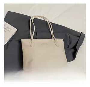 Dettaglio della borsa tote crema texture lychee con placca logo in metallo rettangolare