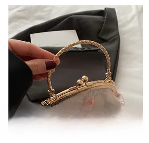 Close-up of vintage butterfly embroidery and embossed gold handle on a beige frame bag