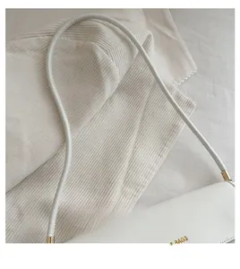 Detail of white leather shoulder strap with gold metal hardware and Bags logo