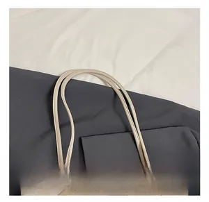 Dettaglio del manico della borsa tote in pelle beige con cuciture rifinite a mano