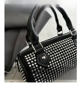 Close-up of black cylinder bag with sparkling silver studs and metal zipper details