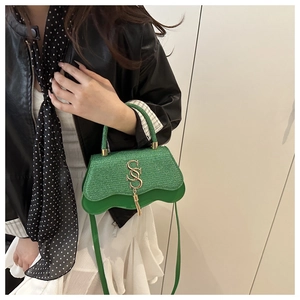Détail du sac bandoulière vert avec tissu pailleté et design de bord en cuir ondulé