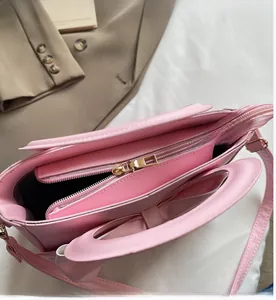 Detail view of pink handbag interior showing smooth gold zipper closure and shoulder strap