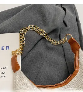 Close-up of golden dual chain strap and woven fabric texture with brown leather trim