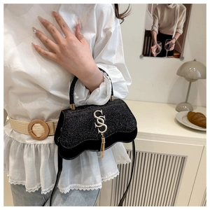 Détail du sac de soirée noir à paillettes avec logo SS doré et pampille à franges