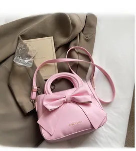 Detail of light pink bow handbag with fashion text and adjustable shoulder strap