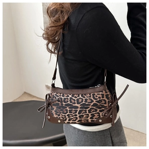 Detail of leopard print bag featuring decorative ribbon bow and silver metal rivets