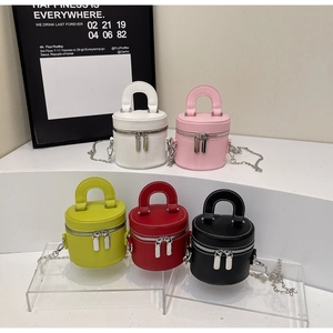 Mini cylinder box bags in five colors with silver chains displayed on a tiered platform
