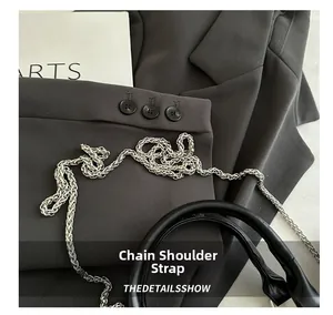 Detail of black leather cylindrical bag with silver woven chain strap and thick handle