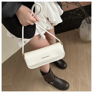 Close-up of a white leather baguette bag featuring gold buckle details and logo print