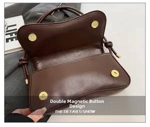 Detail view of the secure double magnetic buckle closure on a dark brown leather handbag