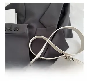 Detail of creamy white leather strap with silver metal hooks on dark grey suit jacket