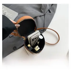 Interior view showing the capacity of a cylindrical brown leather and canvas crossbody bag