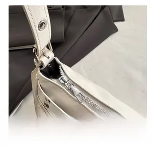 Detail of silver smooth zipper and metal grommets on ivory textured leather handbag