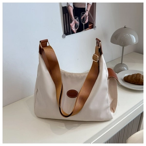 Detail of off-white nylon tote bag with brown leather trim and fashion logo patch
