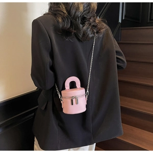Pink bucket bag with silver chain strap shown against a black blazer background