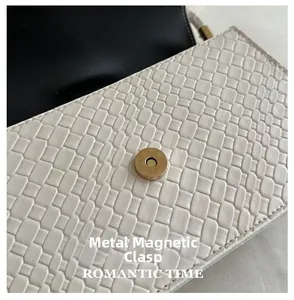 Detail of the high-quality magnetic gold clasp on white woven faux leather shoulder bag