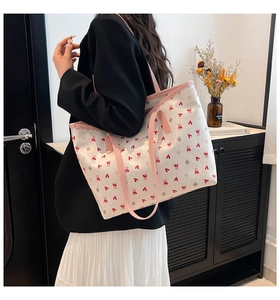 Side view of white tote bag with bear heart prints and pink leather straps on a model