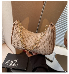 Detail of beige woven hobo bag with a chunky gold chain strap and zipper closure