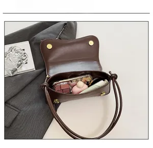 Detail view of brown leather shoulder bag interior showing compartments and daily essentials